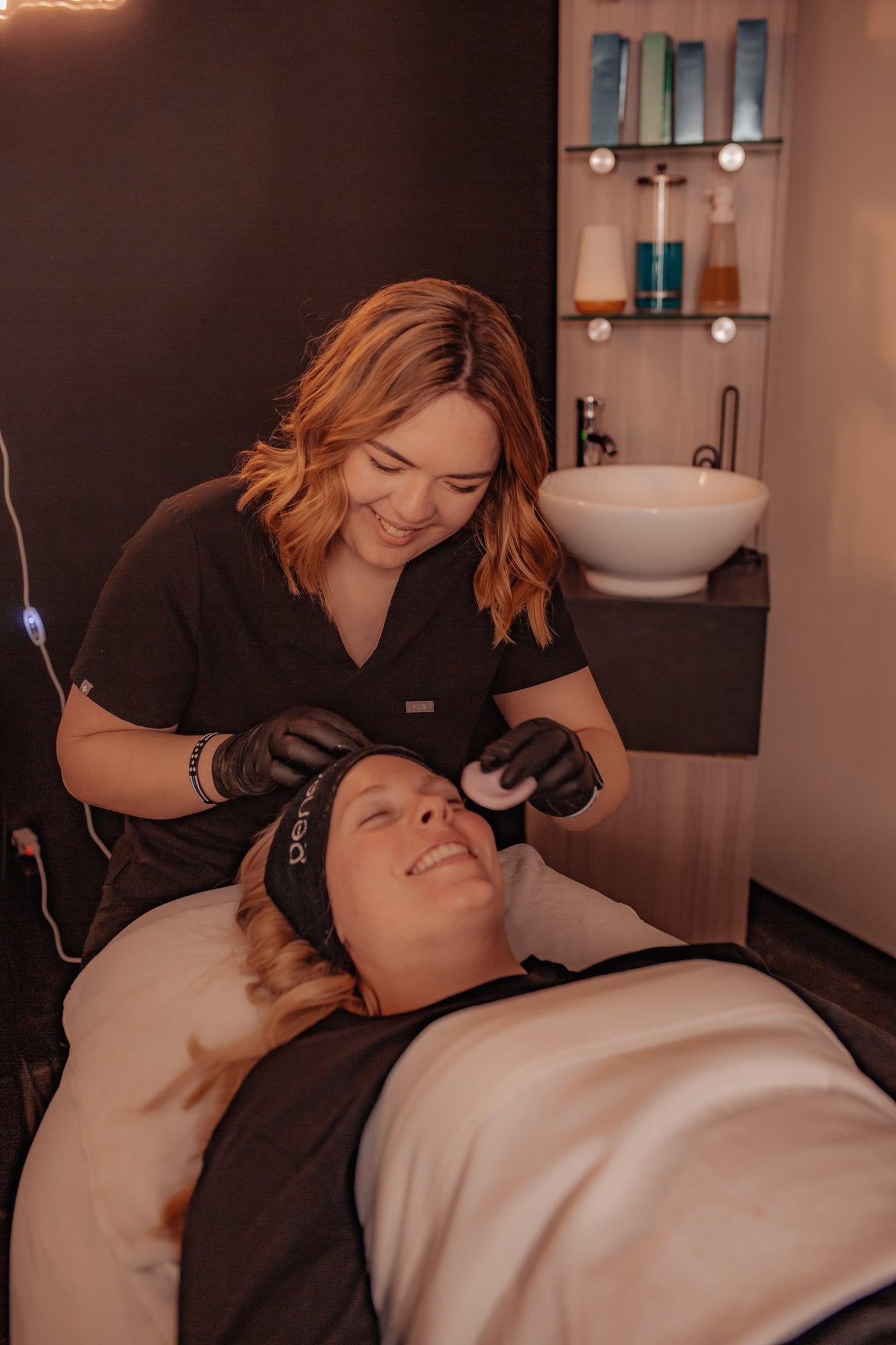 Esthetician and client sharing a smile during a facial treatment